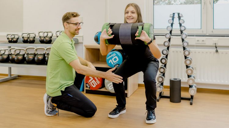 Therapeut und Patientin trainieren mit Bällen