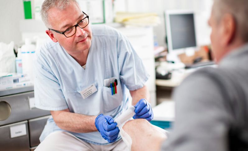 Pflegekraft verbindet Hand eines Patienten