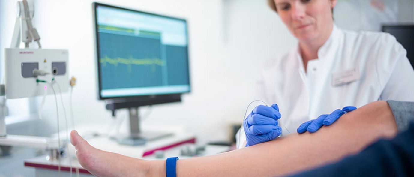 Ärztin misst Nervenleitgeschwindigkeit im Bein eines Patienten