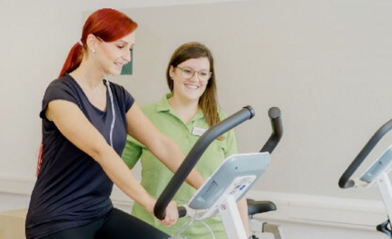 Therapeutin begleitet Patientin beim Ergometertraining