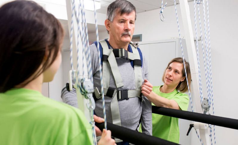 Therapeutinnen begleiten Patienten am Gangtrainer