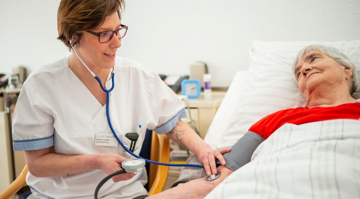 Pflegekraft misst Blutdruck einer Patientin