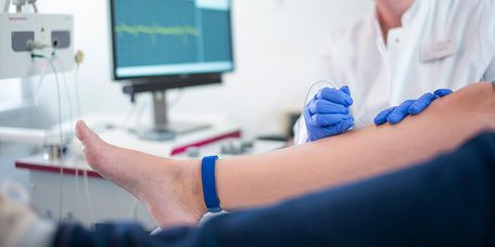 Ärztin misst Nevernleitgeschwindigkeit im Bein eines Patienten