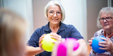 Therapeutin und ältere geriatrische Patientinnen halten Bälle in den Händen