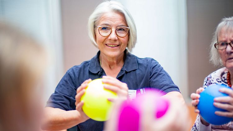 Therapeutin und ältere geriatrische Patientinnen halten Bälle in den Händen