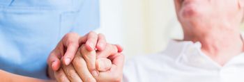 Pflegerin hält die Hand eines älteren Patienten
