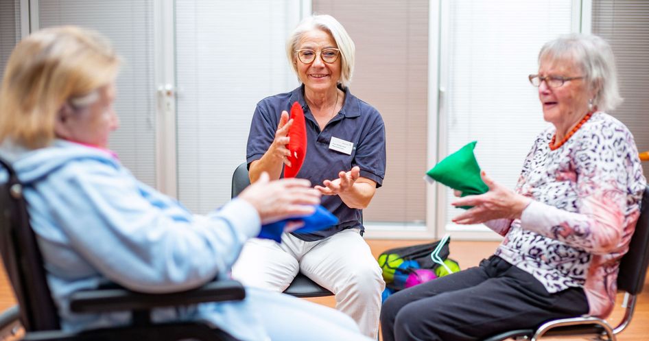 Therapeutin trainiert mit zwei älteren Patientinnen in der Bewegungstherapie