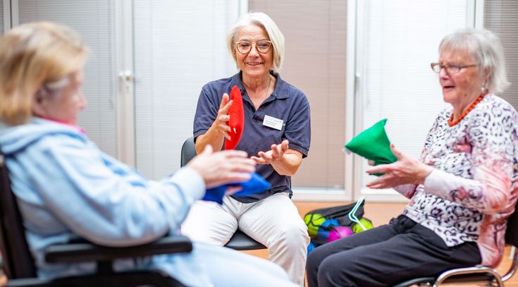 Therapeutin trainiert mit zwei älteren Patientinnen in der Bewegungstherapie