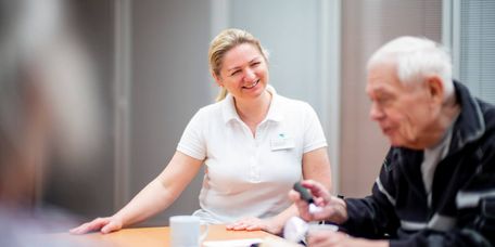 Logopädin und älterer Patient legen Worte aus Buchstaben