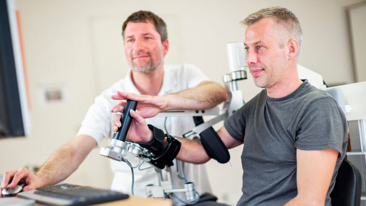 Patient trainiert mit Therapeuten im Armlabor