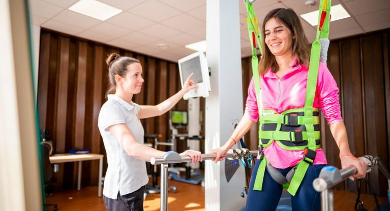 Therapeutin überwacht Patientin im Gehtrainer