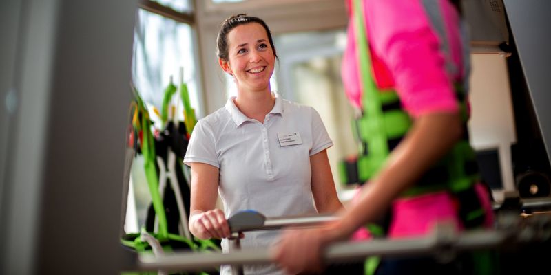 Therapeutin unterstützt Patienten beim Gangtraining