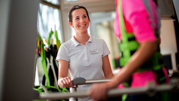 Therapeutin unterstützt Patienten beim Gangtraining
