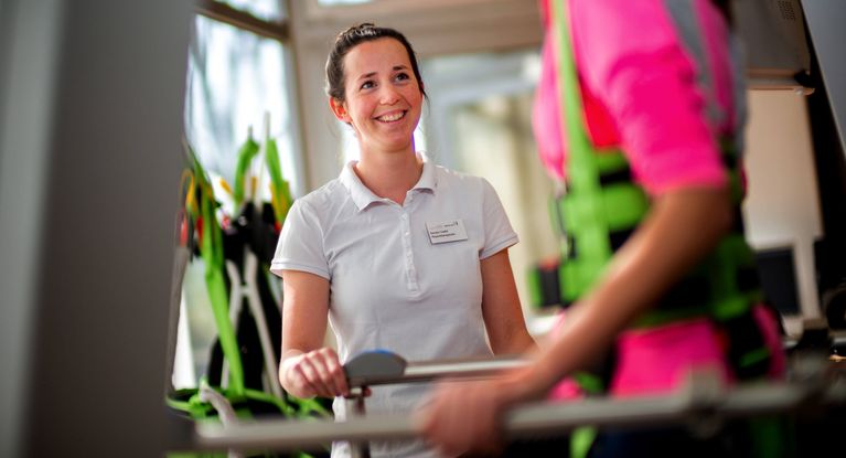Therapeutin unterstützt Patienten beim Gangtraining
