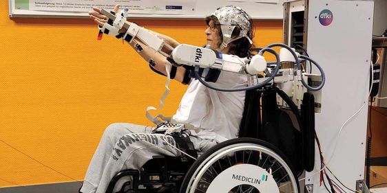 Eine Patientin im Rollstuhl trainiert in einem Exoskelett
